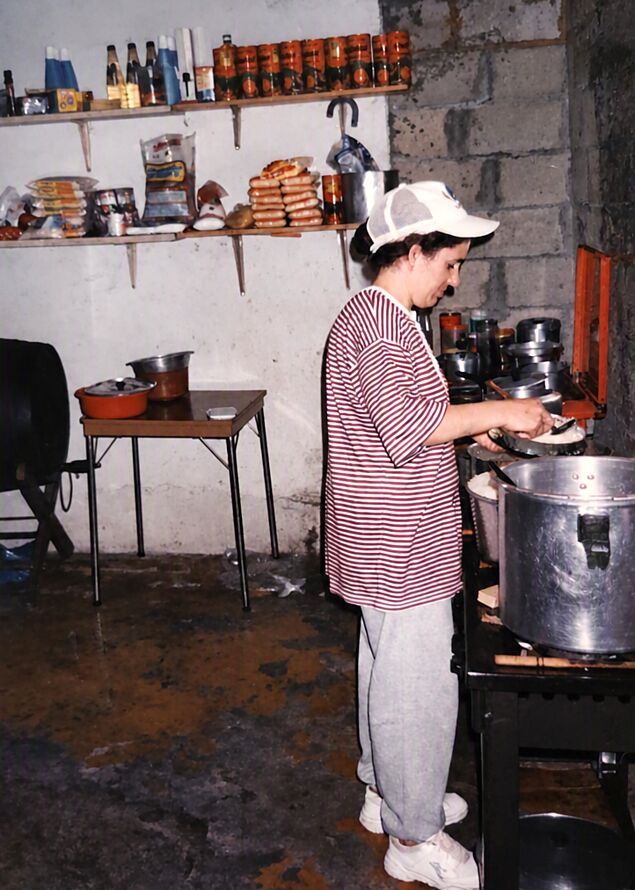 Salomé cozinhando na cozinha de casa em Nova Era, com a panela grande no fogão