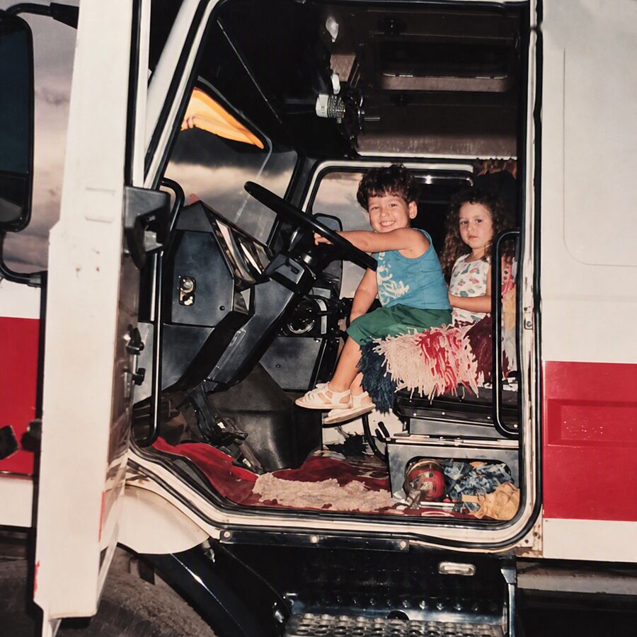 Ana e André crianças, sentados ao volante do caminhão de Argemiro
