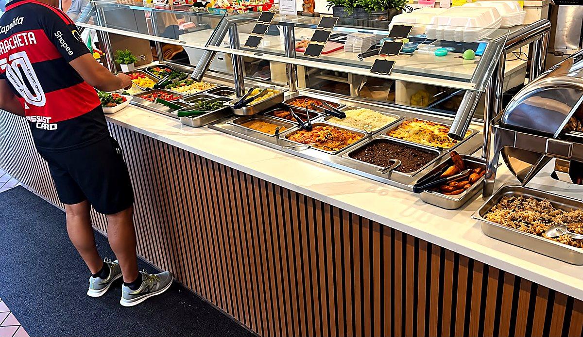 Buffet brasileiro em serviço no almoço, com cliente se servindo — Meritíssimo, Fitchburg MA